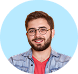 Smiling man with glasses, beard, and short brown hair wearing a red shirt and blue plaid shirt, set against a blue circular background.